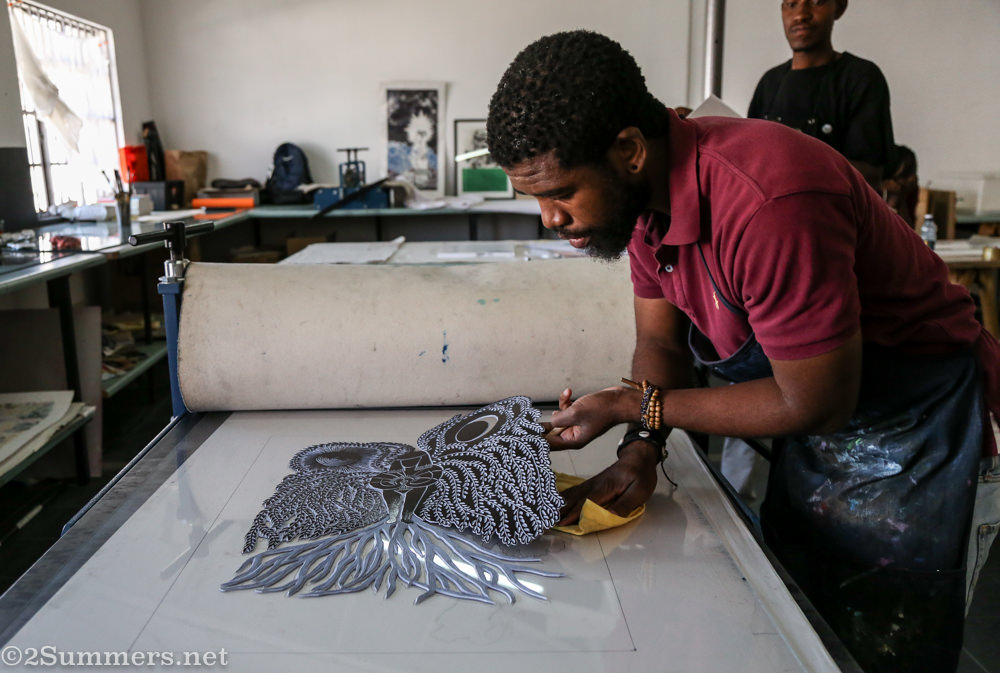 Sanele places the linocut on the press