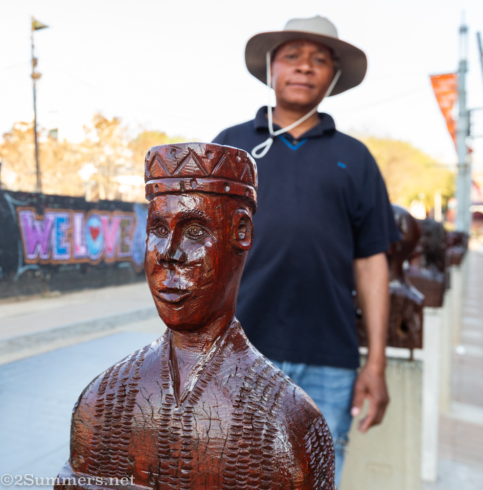 Artist Americo Guambe with his heads